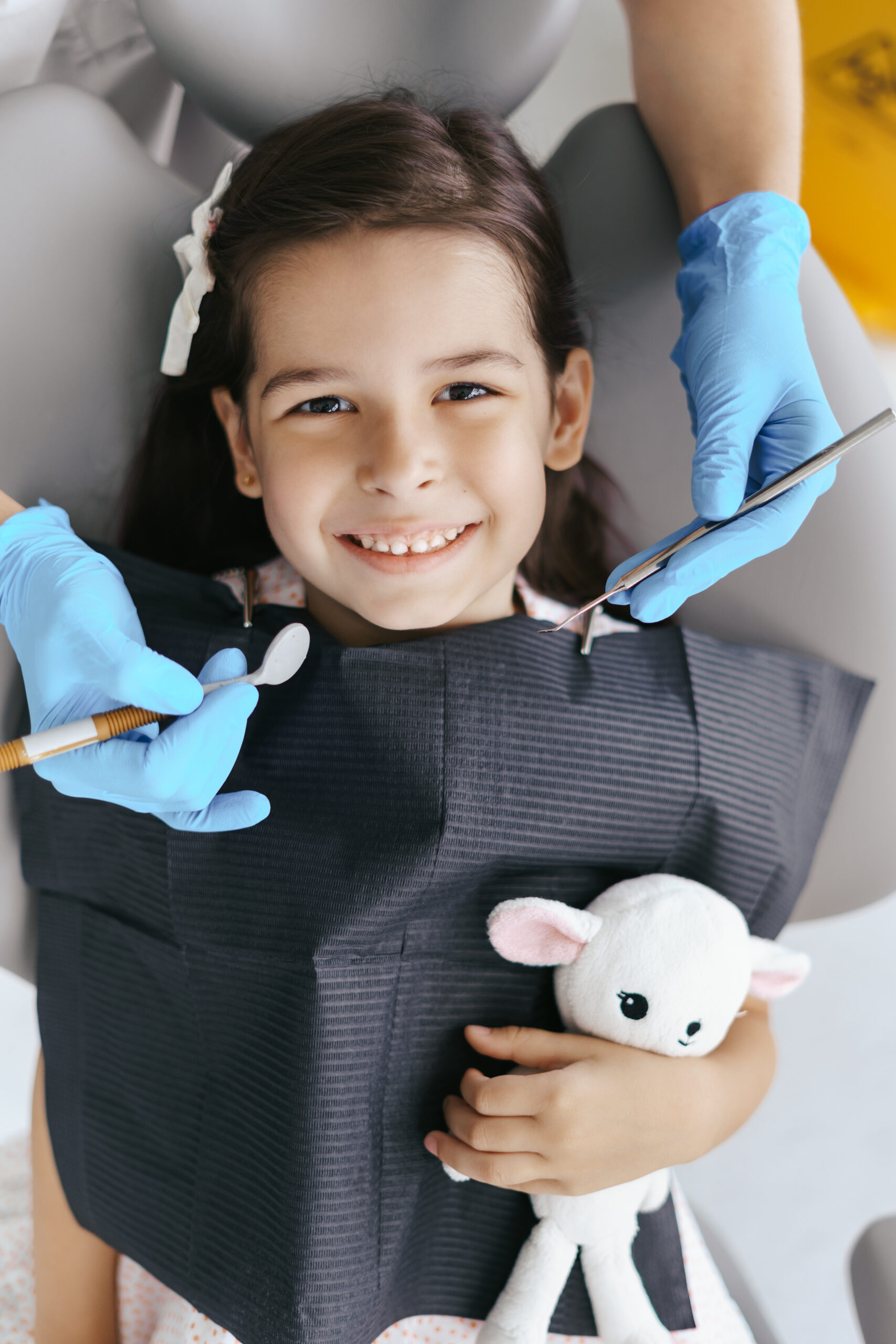 Cute little girl sitting on a modern dental chair and having dental consultation with dentist